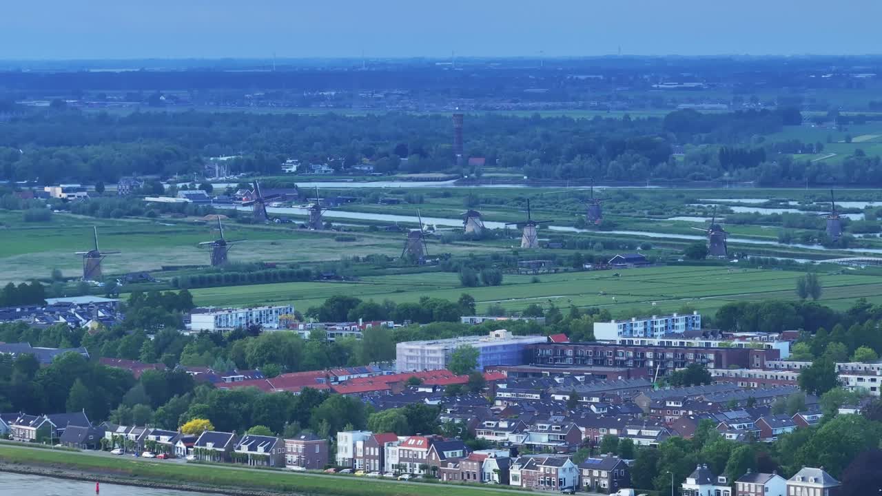 킨더디이크 (kinderdijk) 의 배경에 있는 밀의 공중 뷰와 함께 강 크루즈 가게가 지나가고 있습니다.