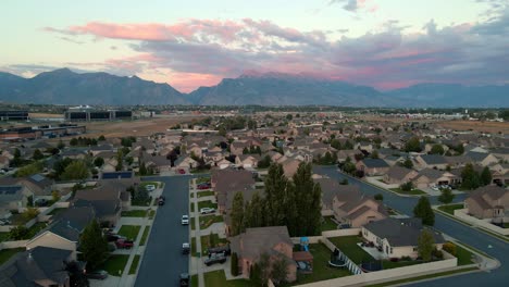 Vista-Aérea-Deslizante-De-Un-Barrio-Suburbano-Al-Atardecer-En-Un-Valle-Debajo-De-Las-Montañas-Wasatch-Front-En-Lehi,-Utah