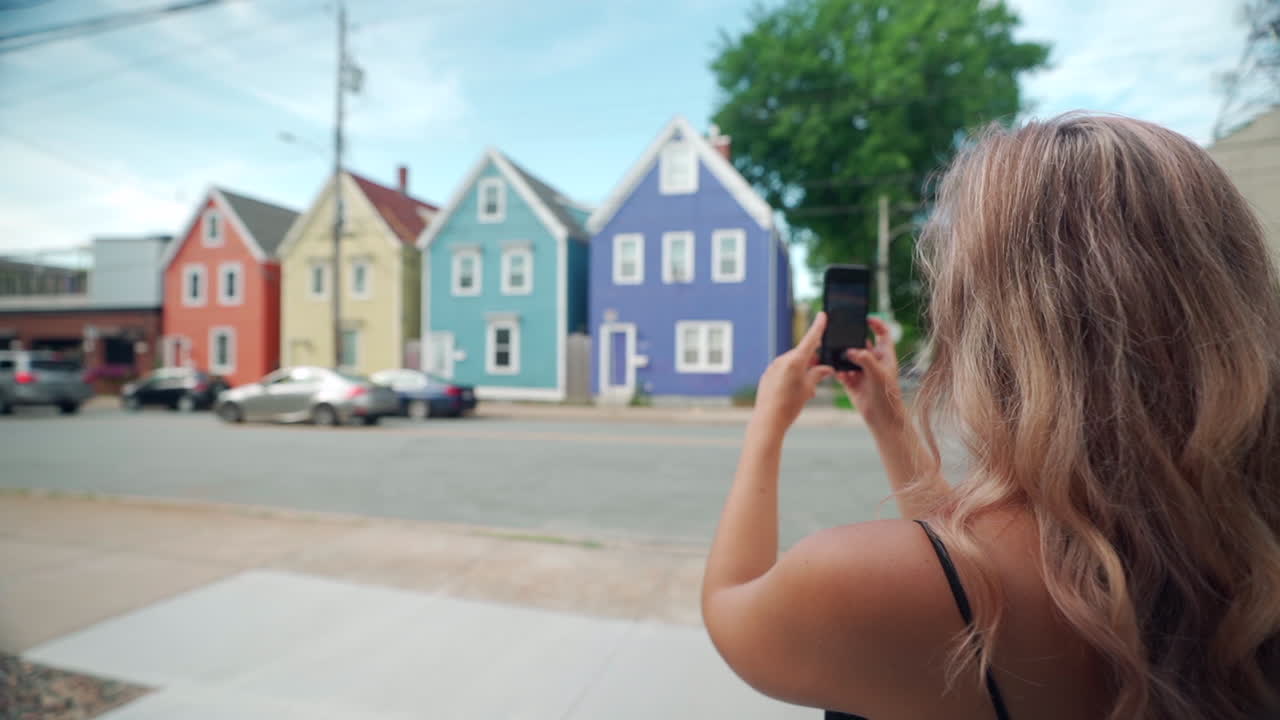 Kvinde tager billede af farverige bygninger med sin mobiltelefon i Halifax, Nova Scotia, Canada