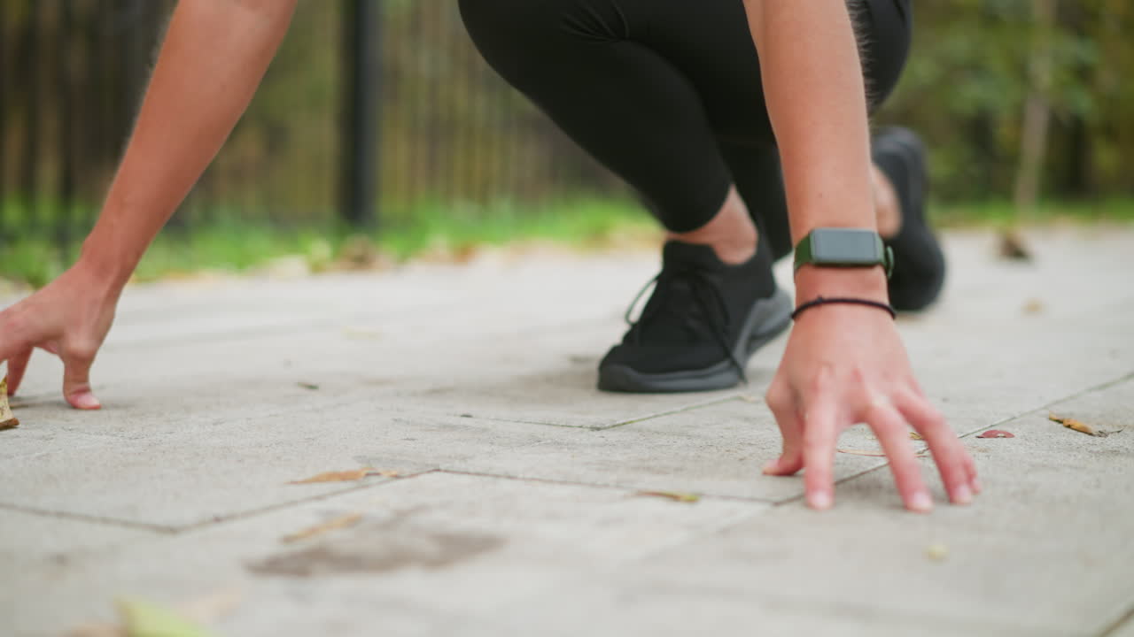 Partial view of girls hands placed on ground, preparing for sprint, focused on setting position, athletic stance, outdoor exercise, fitness training, ready to run, motion blur, dynamic movement