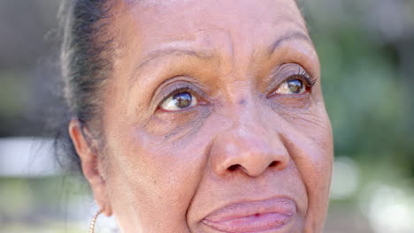 Elderly woman in garden looking thoughtful, enjoying peaceful moment in nature