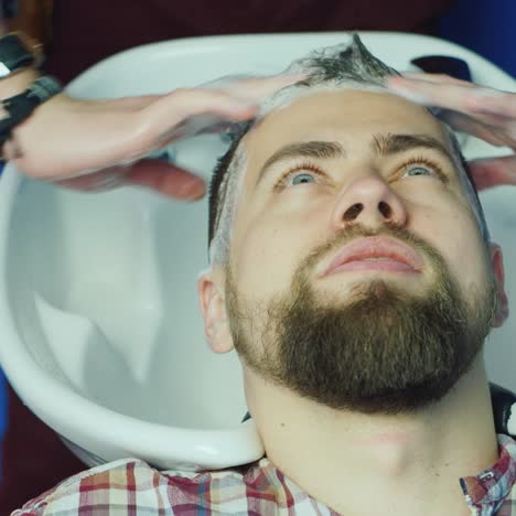hombre lavándose el pelo en la barbería