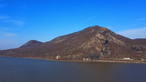 aerial drone footage approaching the appalachian mountains over a river in new york's hudson valley during early spring at breakneck ridge and the hudson river