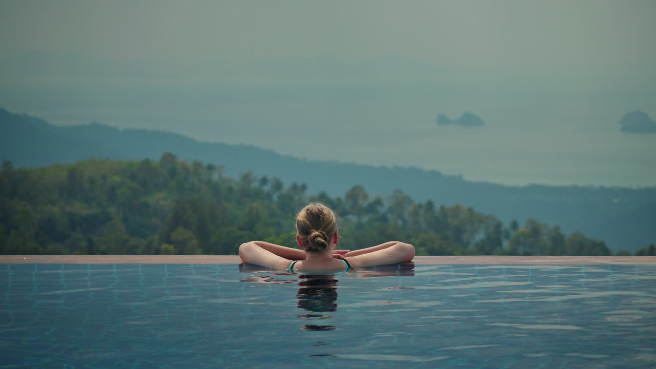 Eine Frau entspannt sich im Infinity-Pool mit Meerblick