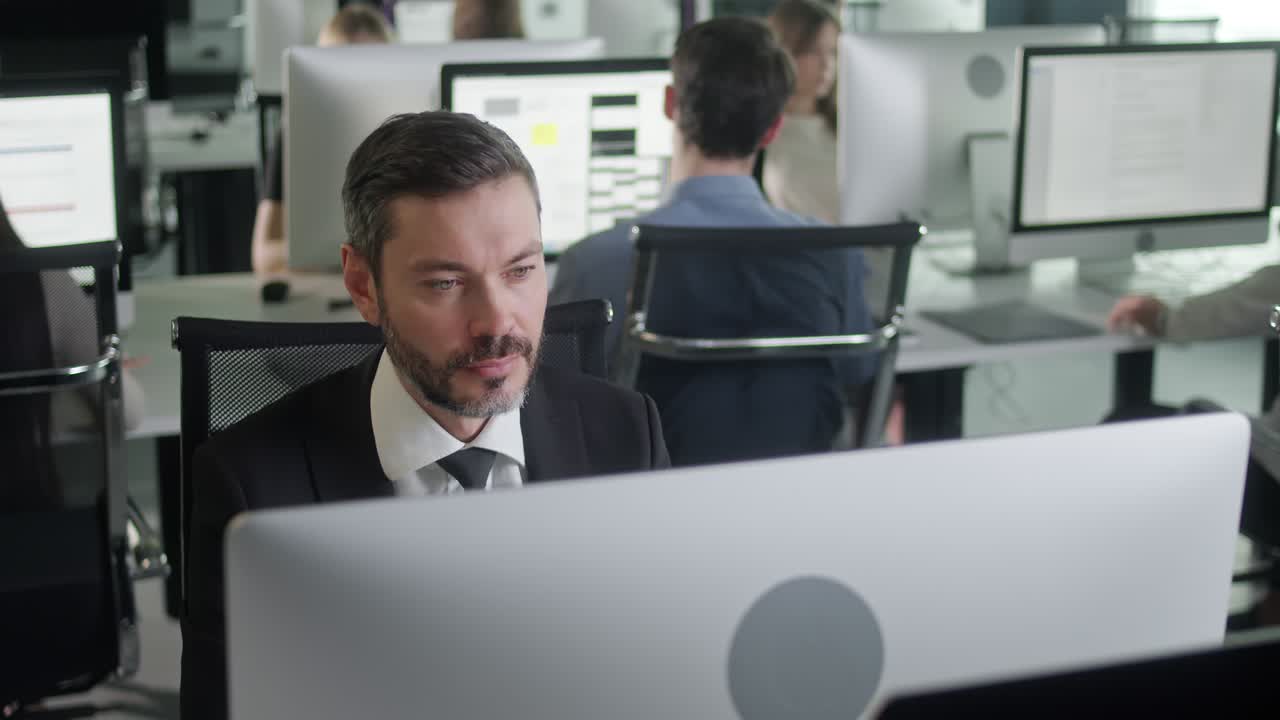 retrato de un joven empresario en una oficina de espacio abierto trabajando en una computadora de cubierta. hombre profesional escribiendo en el teclado de la pc. retrato de hombre de negocios positivo mirando la pantalla de la computadora