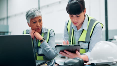 two women in a factory setting discuss a project