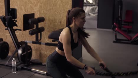 Strong-sportive-brunette-girl-in-her-20's-performing-battle-ropes-workout-at-the-gym.-Slow-motion-footage.