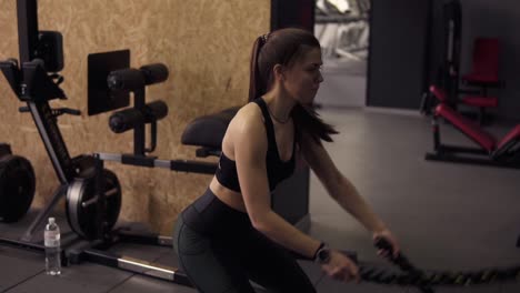 Chica-Morena-Fuerte-Y-Deportiva-De-Unos-20-Años-Realizando-Ejercicios-De-Cuerdas-De-Batalla-En-El-Gimnasio.-Metraje-En-Cámara-Lenta.