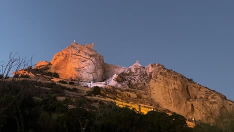 santa barbara castle in alicante from below, lights up and clear blue sky during the summer in spain 4k 30fps