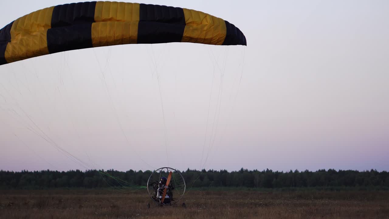 The motor paraglider lowers the parachute after landing and stops completely in the field after sunset