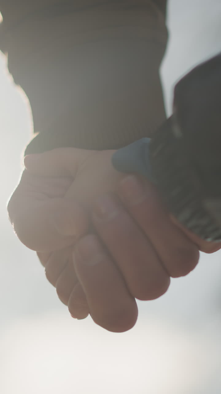 어른과 아이가 손을 잡고, 빛의 부드러운 빛에 비추어, 아이의 손을 부드럽게 고, 나무의 흐릿한 시야를 가지고 있습니다.