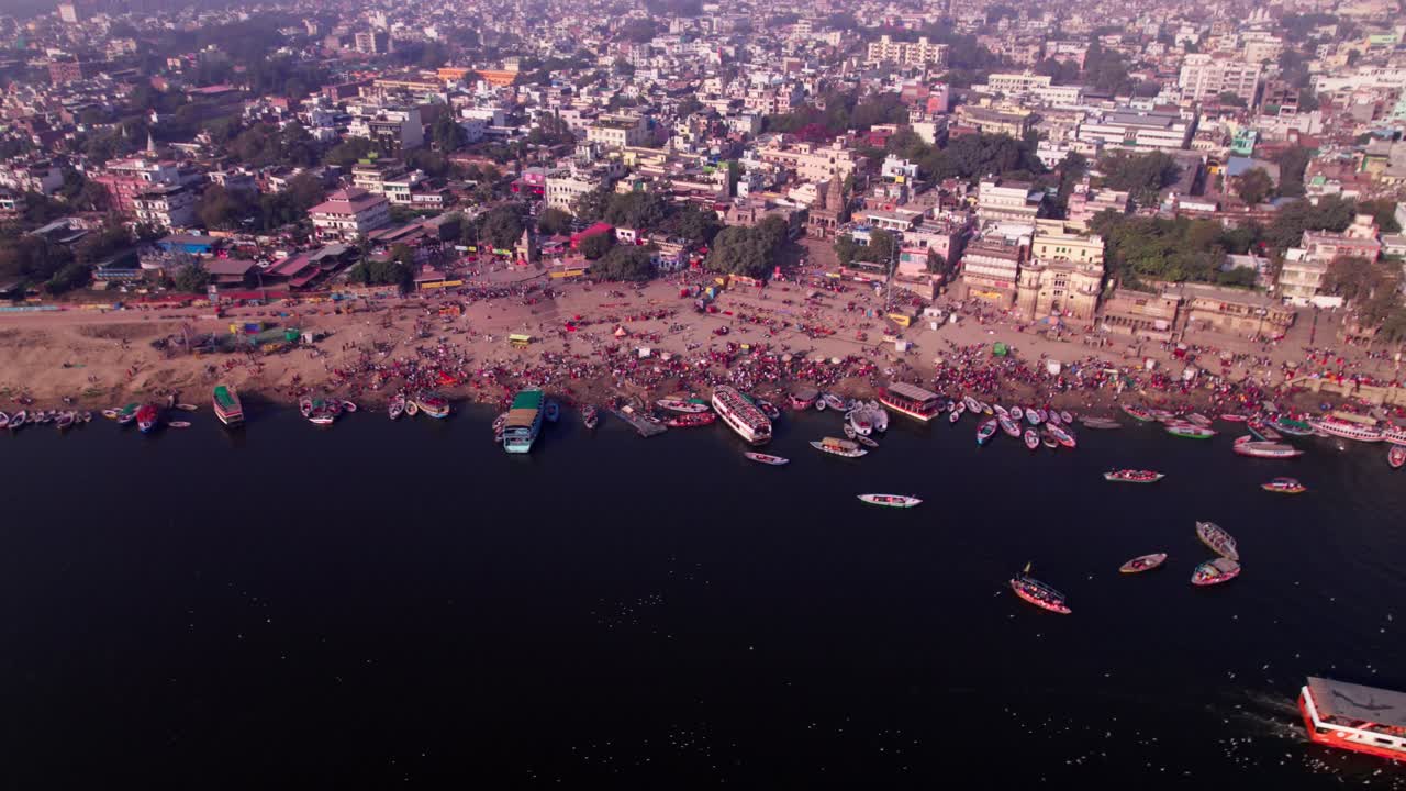 Crowded buildings with ganga river and boats at banaras ghat road kashi, varanasi, uttar pradesh, india. day time, stable shot, drone shot, 4k.