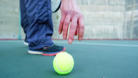 Man-picking-up-tennis-ball