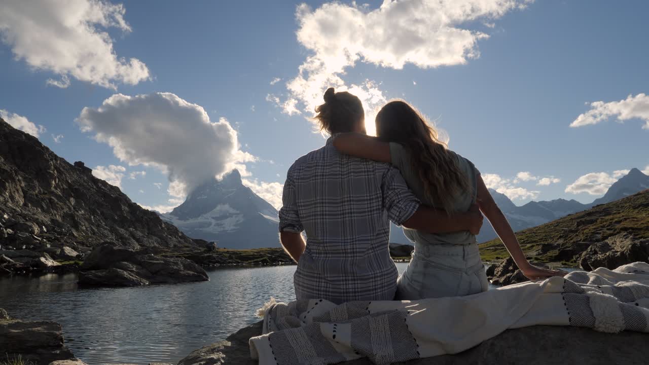 una joven pareja contemplando el impresionante paisaje montañoso cerca del lago alpino, matterhorn peak.