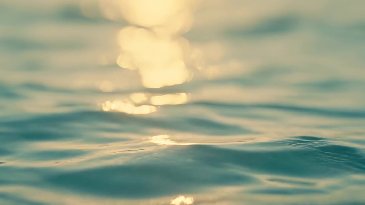 Luce solare dorata che luccica sulla superficie dell'acqua blu-verde