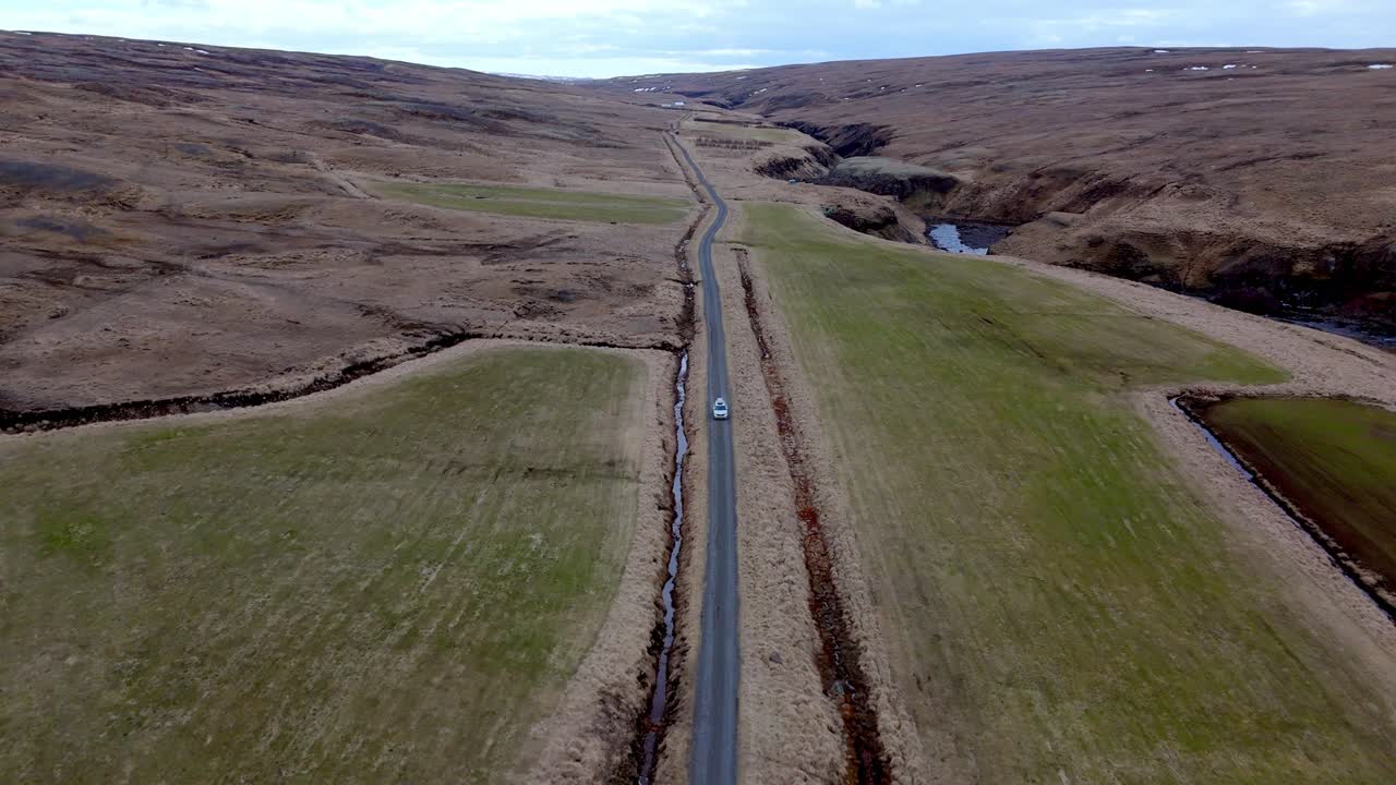 aerial view of car driving in wilderness of Iceland during a road trip with scenic landscape surrounded by nature