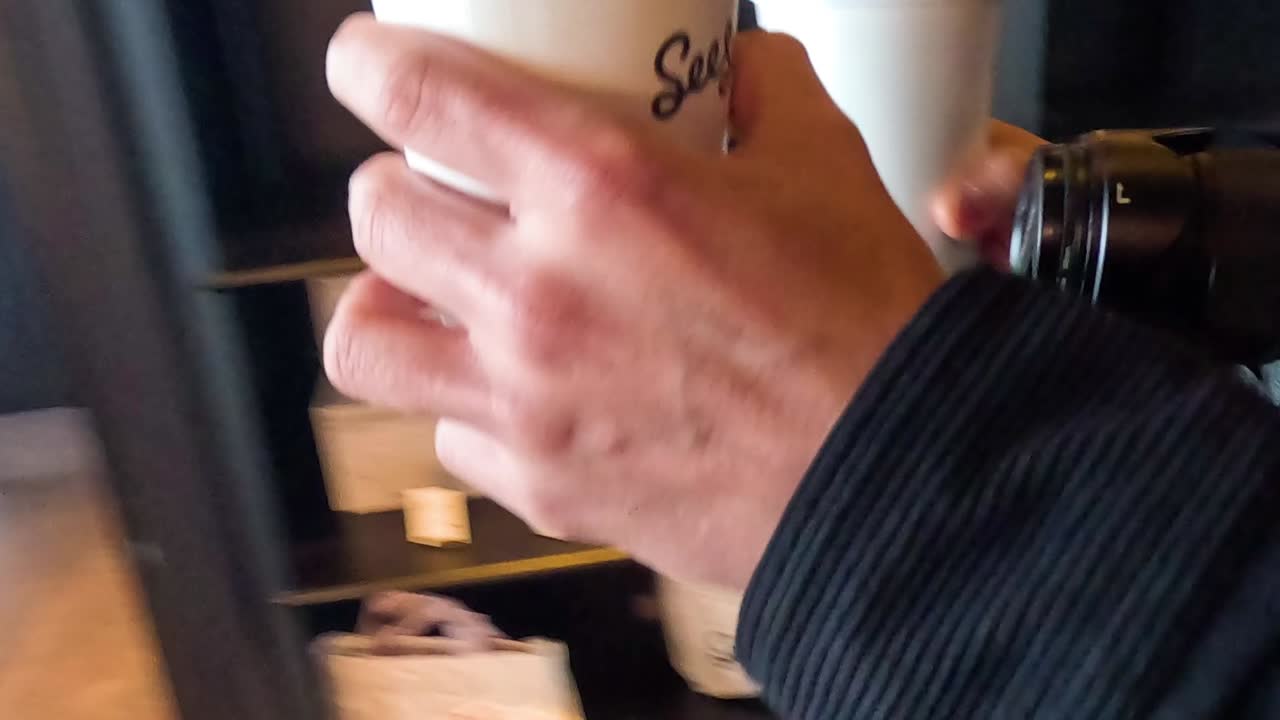 Close-up shots of hands exchanging coffee cups at a cafe counter, focusing on the interaction.