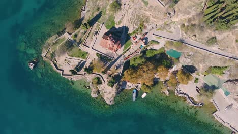 monastery above a pristine turquoise lake spinning drone shot