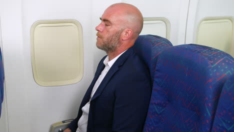 a nervous man with a beard taking deep breaths trying not to panic with anxiety on a passenger plane airliner airplane