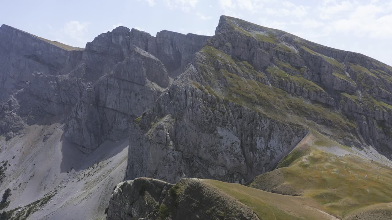 Et luftfoto af bjergtoppe, hvor dronen dykker ned i en af sprækkerne.