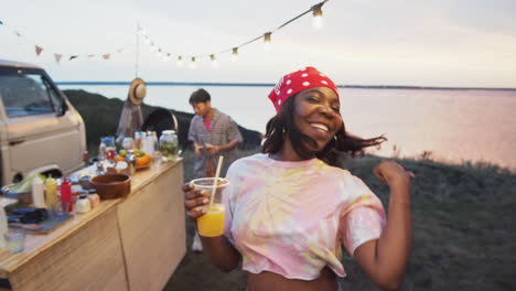 happy african-american woman dancing with drink on summer festival