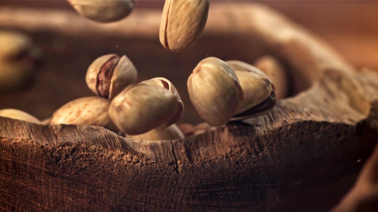 Pistacchi che cadono al rallentatore in una ciotola di legno rustica