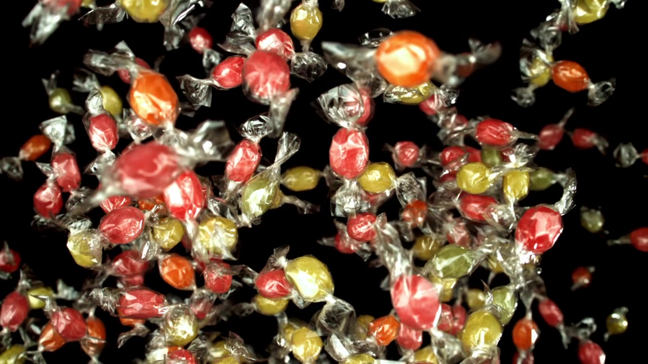 Doces Coloridos Embalados Caindo em Câmera Lenta Contra um Fundo Preto