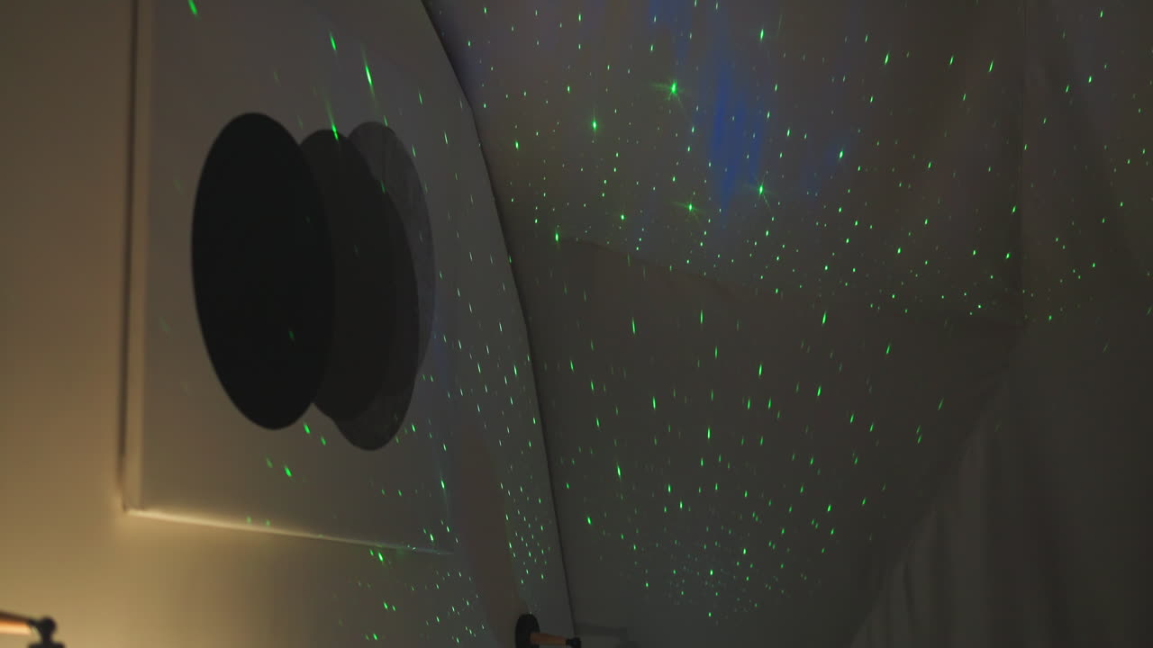 imitación de la luz del cielo estrellado por el proyector en el dormitorio. luces verdes encantadas en la pared semiesférica blanca de la casa de glamping. dispositivo doméstico de cuento de hadas