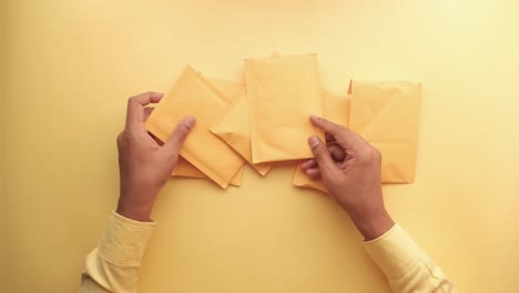 hands holding a stack of yellow envelopes