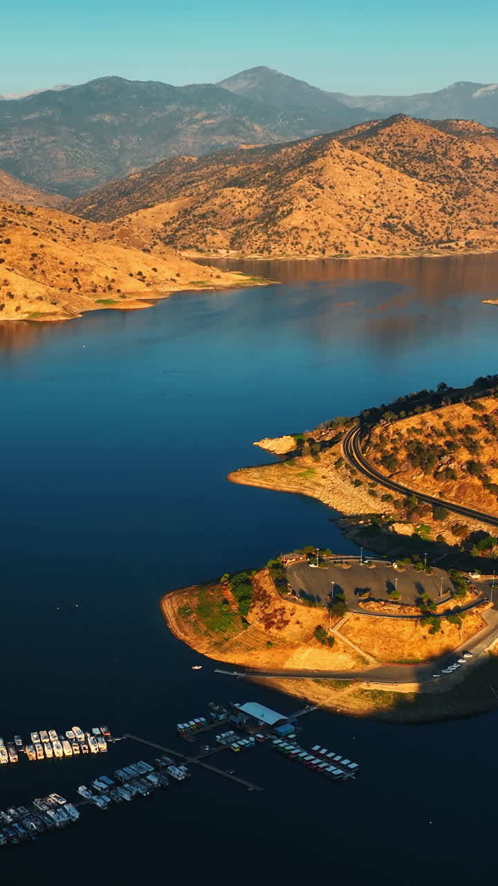 Multiple yacht at the dock on the calm lake. Gorgeous sunlit bare mountains around the lake. Top view. Vertical video