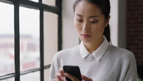 beautiful asian business woman using smartphone at home browsing messages texting on mobile phone enjoying relaxed morning networking