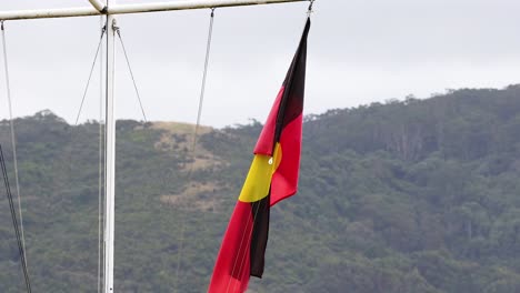 the aboriginal flag waves against a hilly backdrop on a cloudy day, captured in a series of dynamic frames