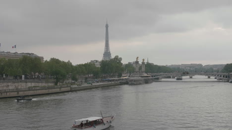 Pariser-Stadtbild-An-Bewölkten-Tagen,-Boote,-Die-Im-Fluss-Seine-Mit-Eiffelturm-Im-Hintergrund-Schwimmen