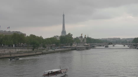 paisaje urbano de parís en un día nublado, barcos flotando en el río sena con la torre eiffel en el fondo