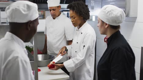 grupo diverso de chefs de pie alrededor de una mesa escuchando instrucciones