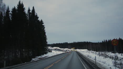 POV-Auto:-Fahren-Auf-Einer-Asphaltierten-Autobahn-Auf-Dem-Land-Mit-Vorbeifahrendem-Verkehr-Von-Helsinki-Nach-Vuokatti,-Finnland,-Auf-Kaltem,-Schneebedecktem-Winterboden-An-Bewölkten-Tagen-In-Der-Abenddämmerung,-Handheld