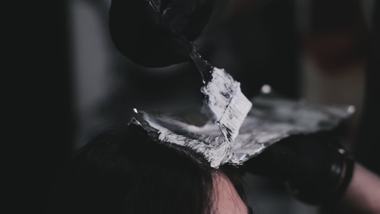 Parrucchiere che tinge i capelli lunghi di una donna in un salone professionale
