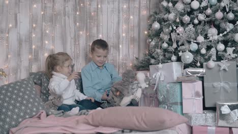un niño lindo con camisa azul claro entretiene a su hermana rubia más joven