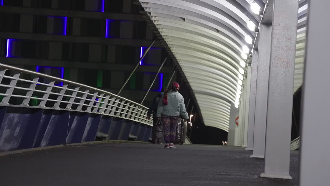 Visitors to the city cross illuminated pedestrian footbridge at night