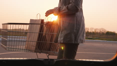 女人的 siluet 打開一輛車的車<unk>,放入紙購物袋