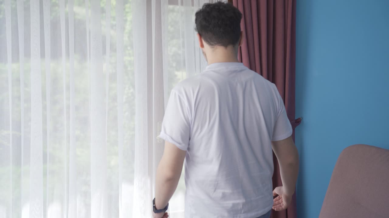 The man who opens the curtains yawns and relaxes.