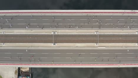 Marathon-runners-crossing-bridge,-aerial-top-down-view-of-people-running