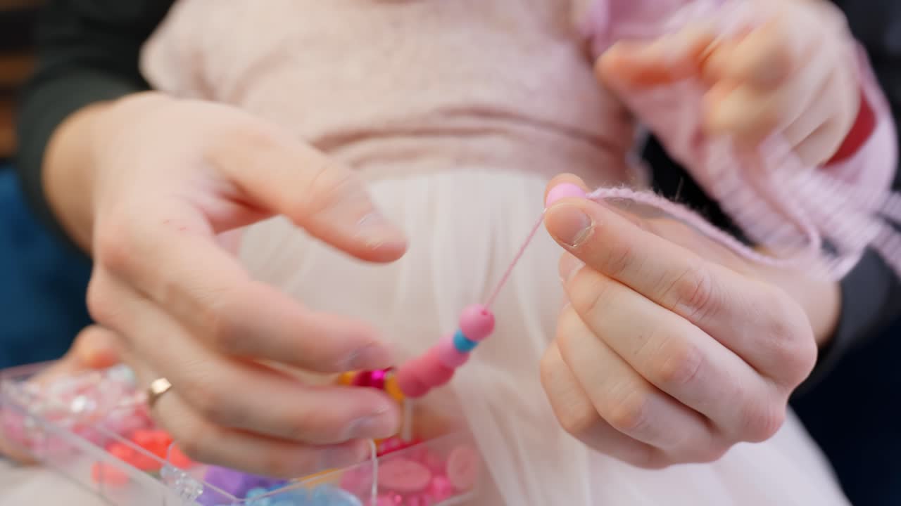 Training child's motor skills with beads and necklace, close up