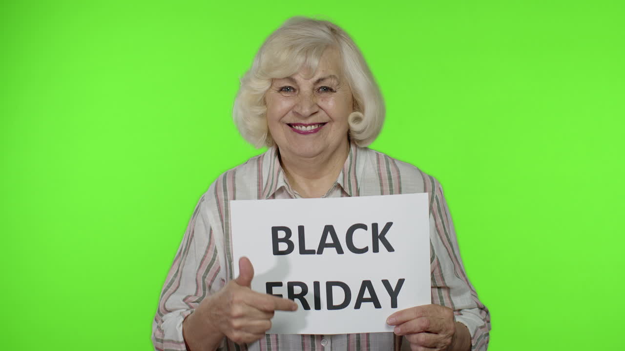 Ældre bedstemor holder et banner med teksten "Black Friday". Senior kvinde glæder sig over rabatter.
