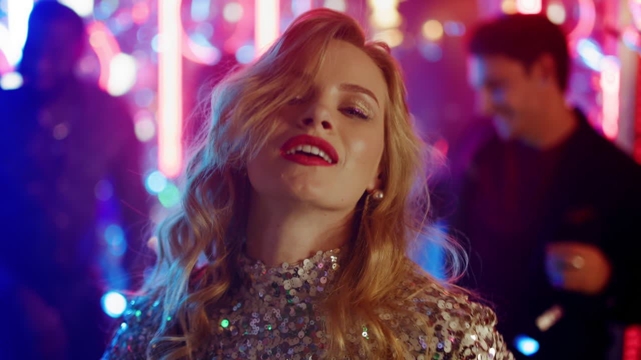 chica rubia mirando a la lente en un club nocturno. mujer joven bailando en la discoteca