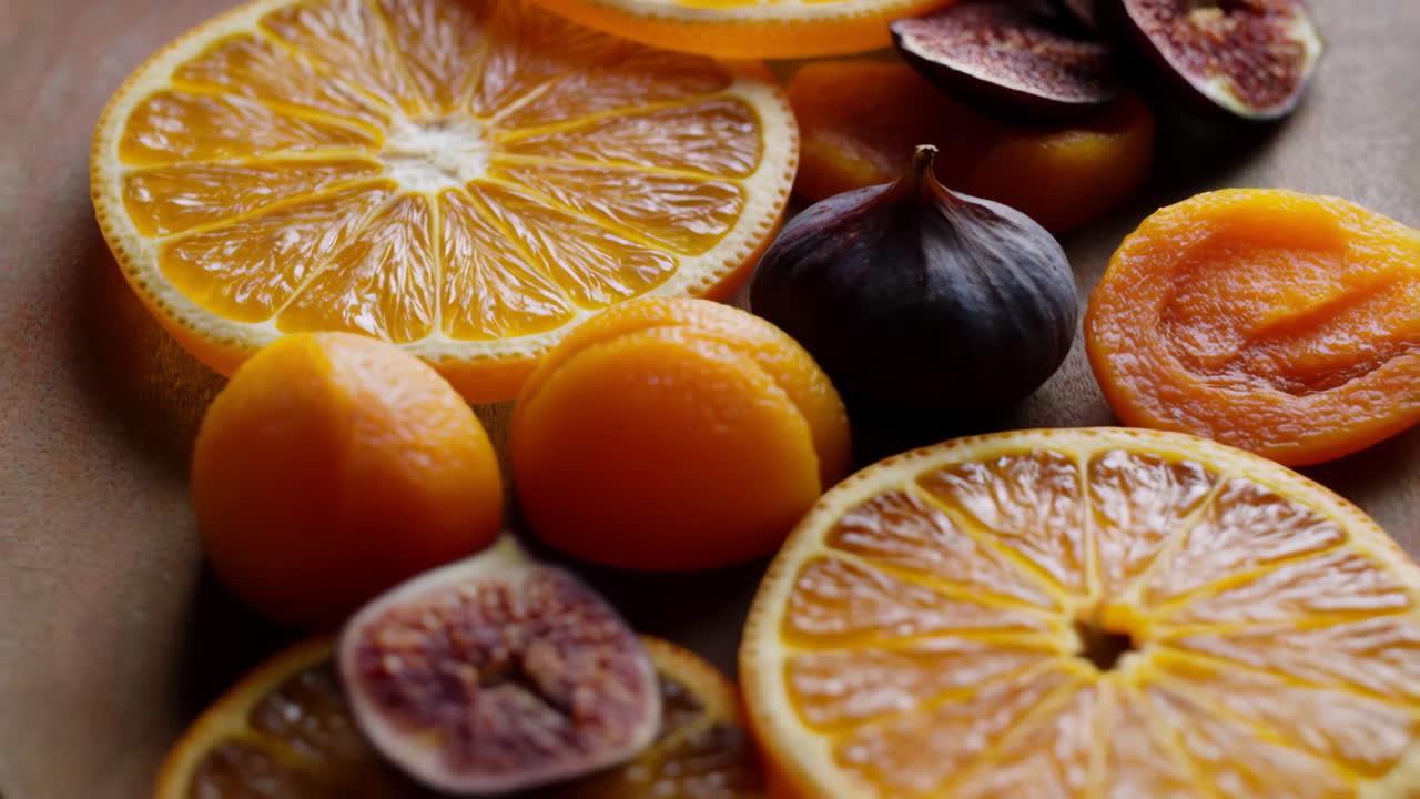 Primer plano de higos en rodajas y albaricoques secos con rodajas de naranja sobre una tabla de madera. Tonos rústicos cálidos y estilo gourmet.