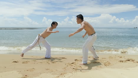 two men dancing capoeira on the beach