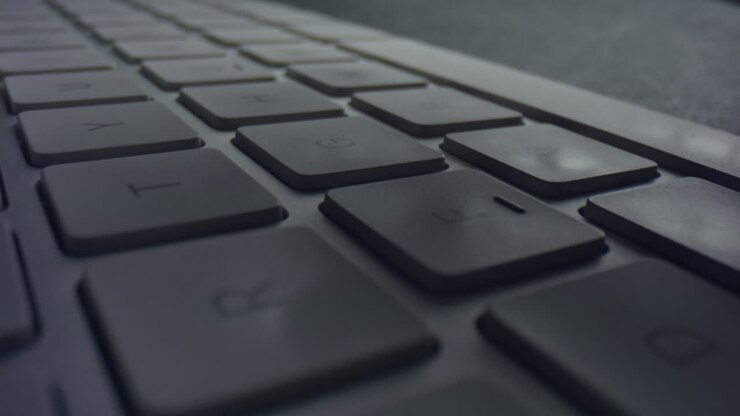 Macro of male fingers pressing white keys on computer keyboard