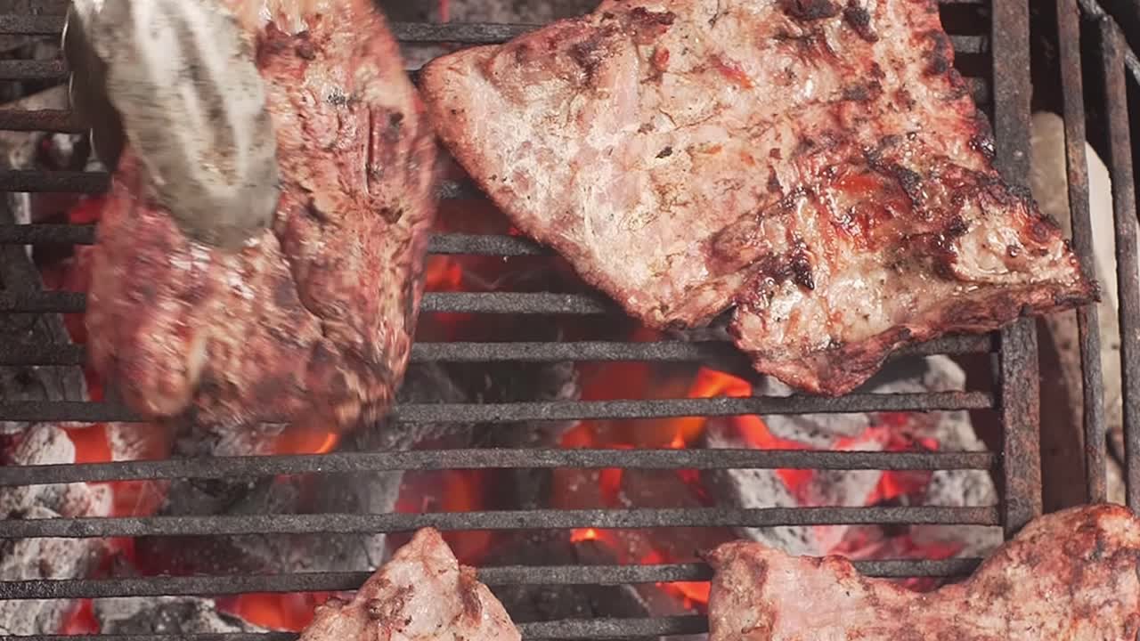 Vista dall'alto di carne al barbecue su fuoco vivo ardente con fiamme.