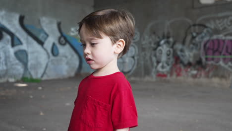 the camera dollies around a young boy in slow motion in an abandoned gritty warehouse